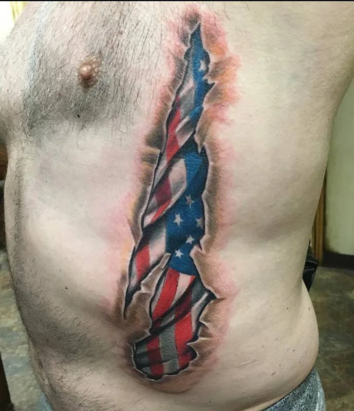 Heather Baldwin realism American flag tattoo with 3D skin-tear effect on ribs, Hawaii
