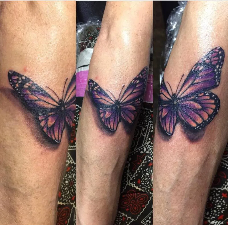 Heather Baldwin color realism butterfly tattoo on forearm — purple monarch, 3D effect, Hawaii